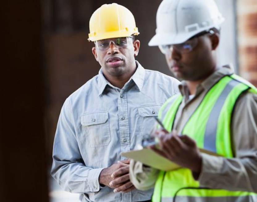 Two construction workers are standing next to each other.