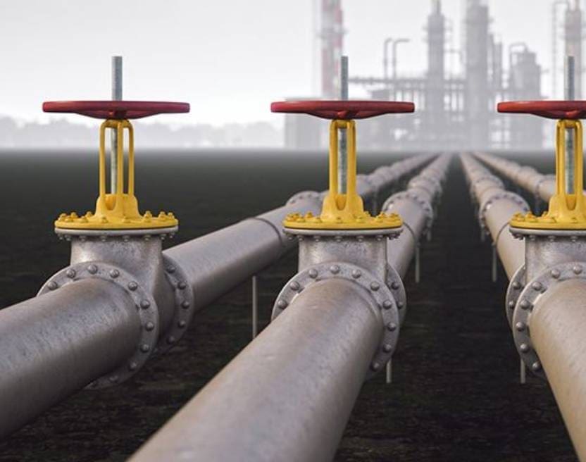 Three pipes with valves on them in a field.