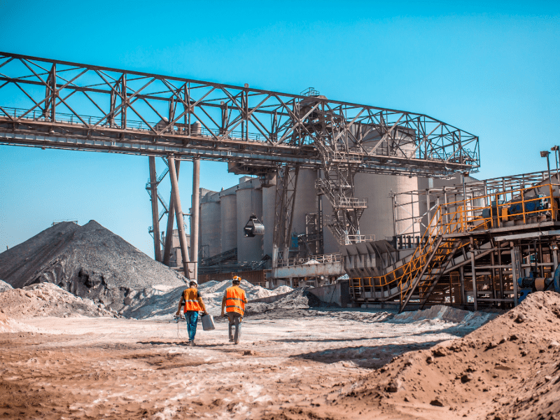 Industrial site with two workers walking outside.