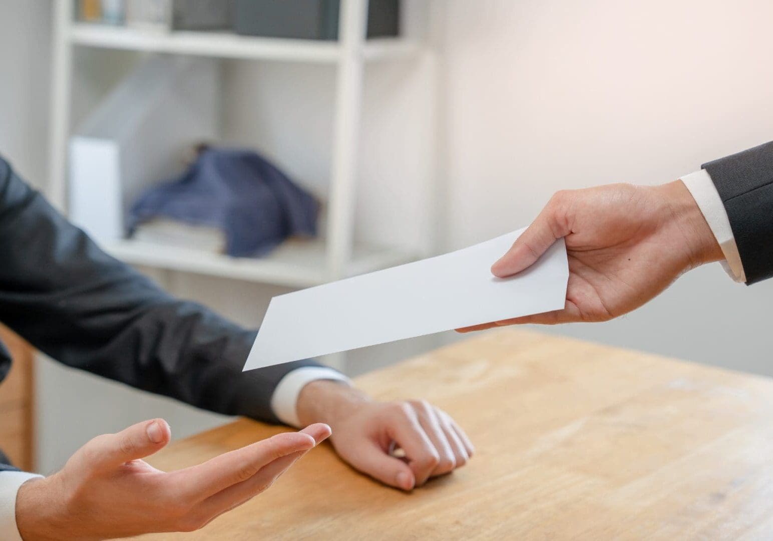 Hand passing white envelope across desk